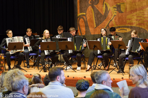 Ein großes Akkordeonensemble musiziert.