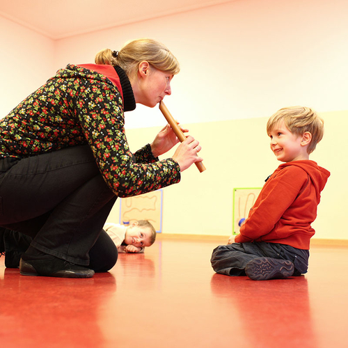 Musiklehrerin spielt Vorschulkind auf Blockflöte vor