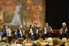 Ein großes Akkordeonensemble musiziert.